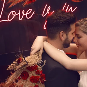 Novios junto a neon de boda Love is in the air